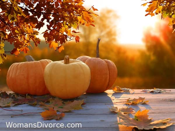 Pumpkins outside on wood table with autumn leaves