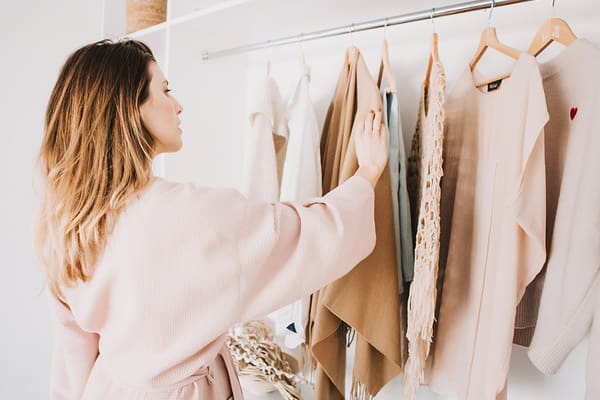 Woman choosing between different clothes in her closet in the process of reinventing her style