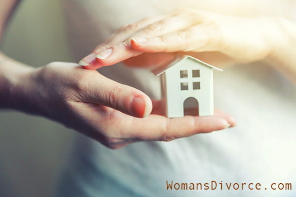 Woman with miniature house in hands signifying buying a house after divorce